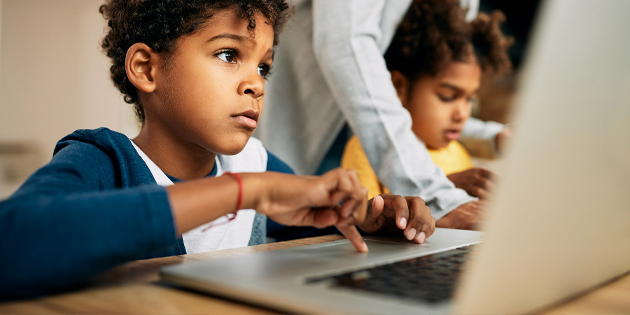 Criança usando o computador sob orientação da professora