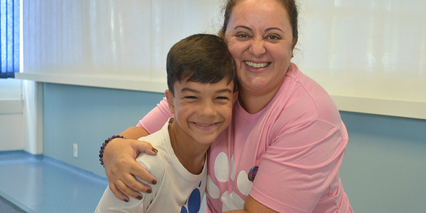 Professora abraçada com o aluno, ambos sorrindo